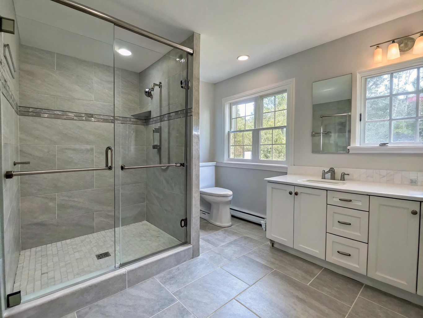 Accessible modern bathroom featuring a curbless walk-in shower with safety handrails and slip-resistant floor tiles