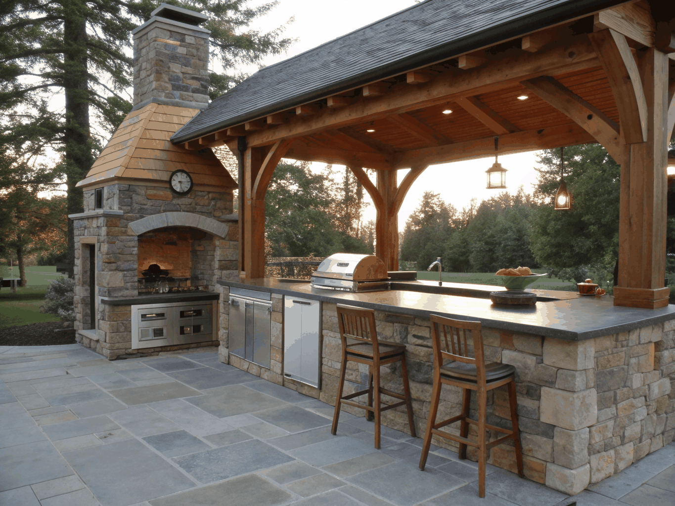 Custom outdoor living space with natural stone fireplace, built-in outdoor kitchen, and covered patio in a Georgia backyard